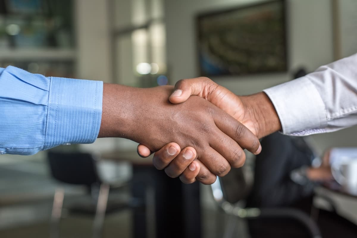 Close-up of two people shaking hands across a table in an office meeting room