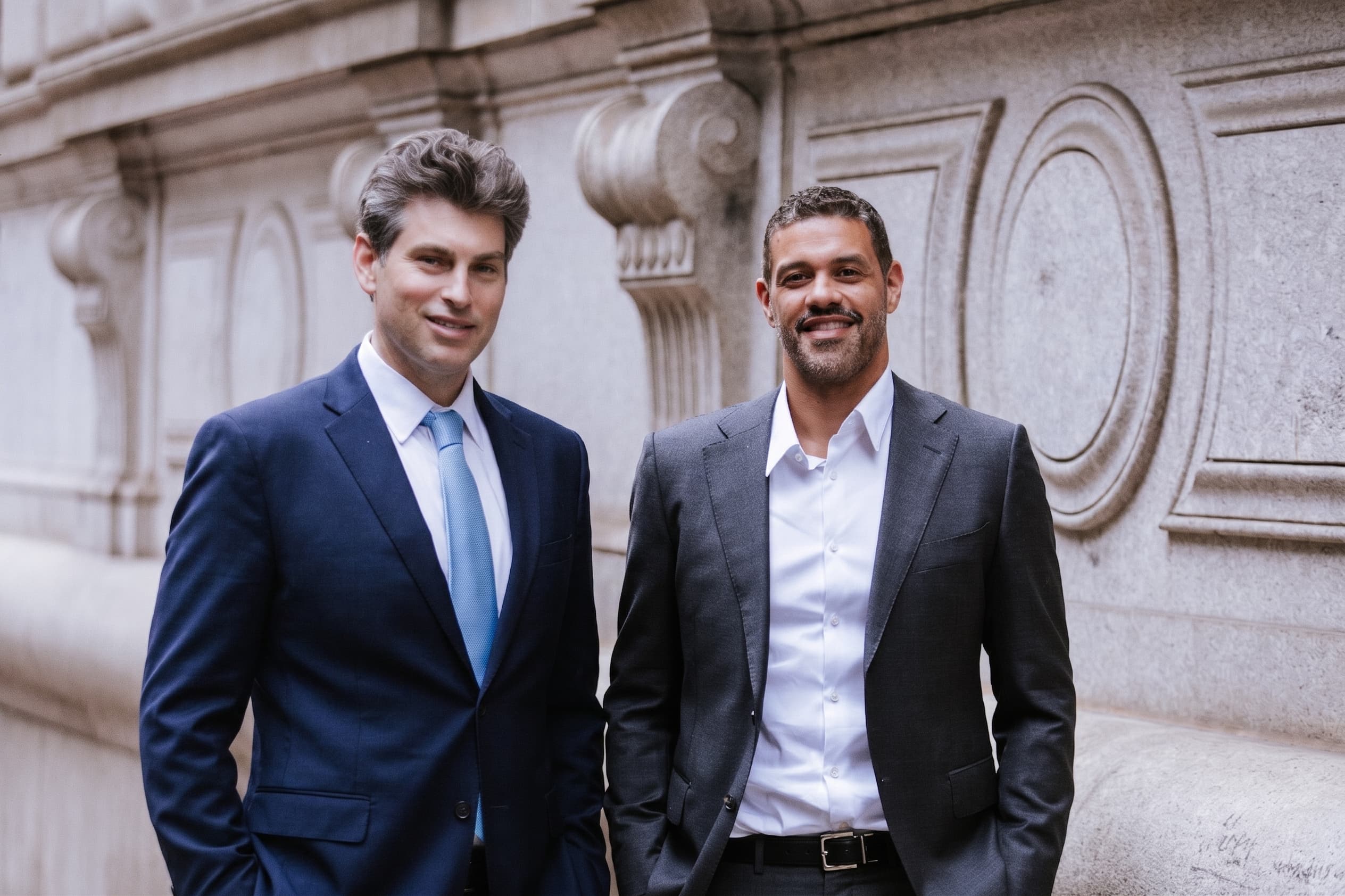 The two founding partners of Freundlich & Littman, LLC standing side by side outside a stone office building